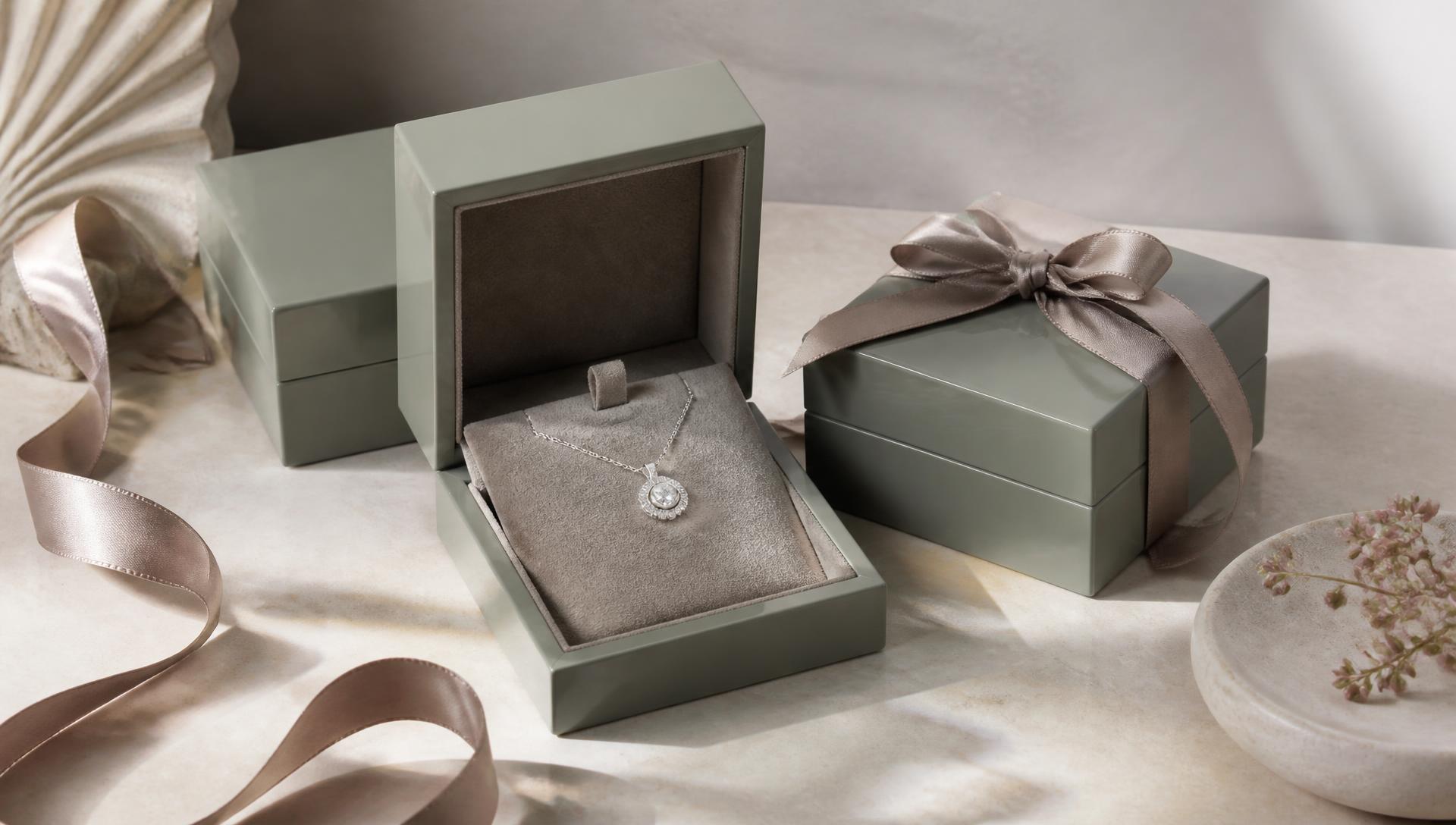 A diamond pendant in a carbon gift case beside an engraved card